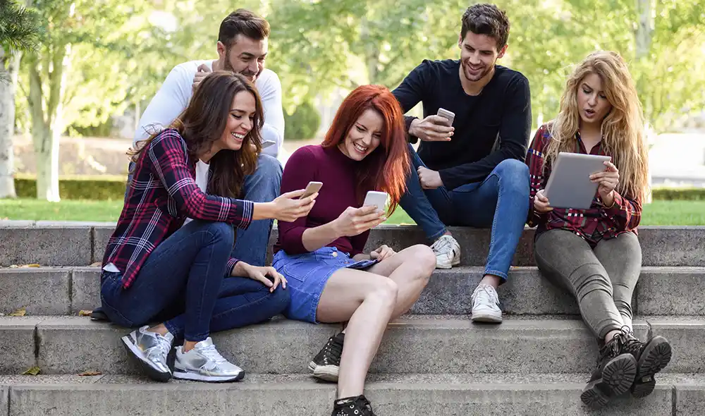 a group of young people at BudaPart playing the Landventure outdoor escape game on their smartphones