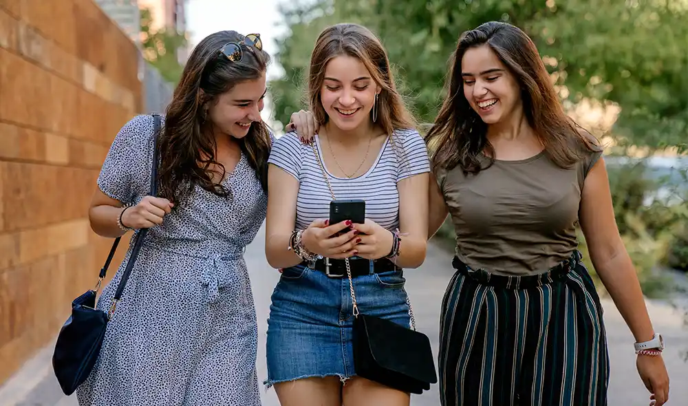 three young women at BudaPart playing the Landventure outdoor detective game on their smartphones