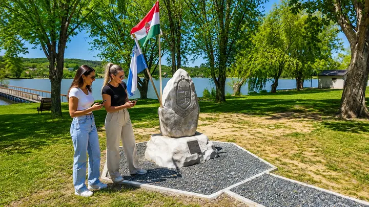 két nő okostelefonnal Landventure szabadtéri szabadulós játékot játszik Csepregen, a Bene-hegyi tó mellett a Mementó kőnél