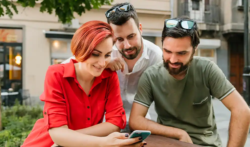 két férfi és egy nő okostelefonnal Landventure városi nyomozós játékot játszik Debrecen belvárosában