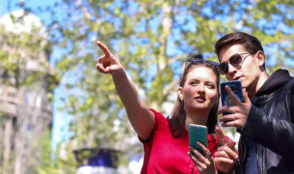 a young couple holding smartphones is thoughtfully pointing into the distance in downtown Esztergom