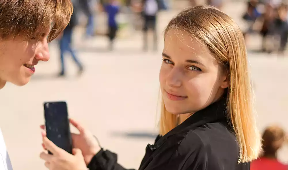 a young woman and man are playing the Landventure detective game on a smartphone in downtown Esztergom