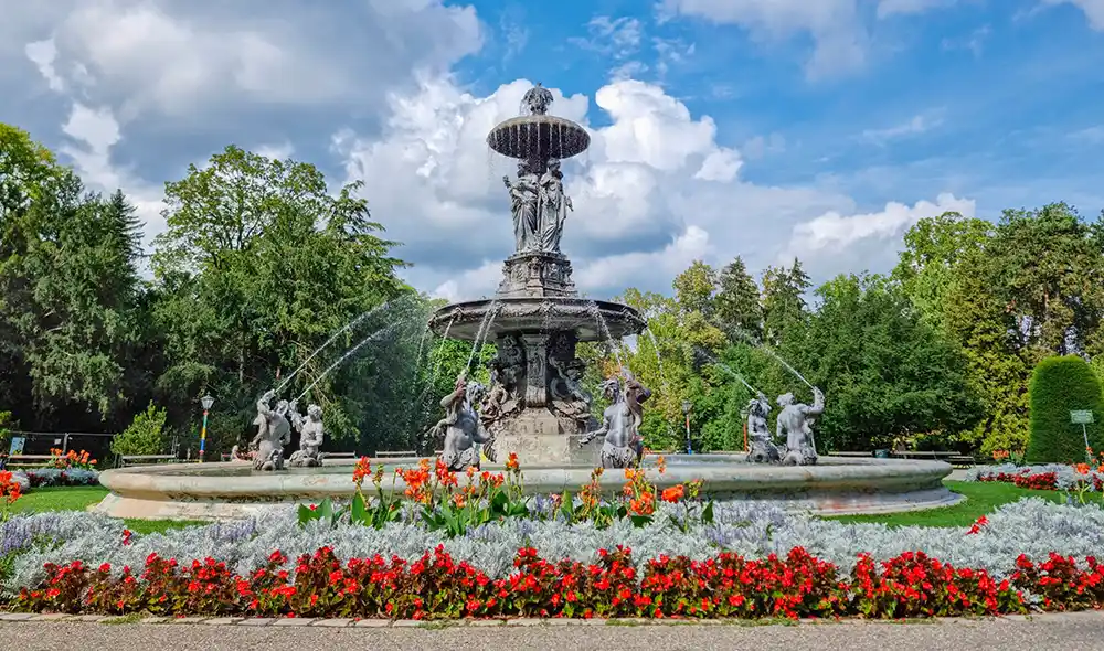 der prachtvolle Brunnen im Stadtpark Graz, umgeben von bunten Blumen, ist Teil einer spannenden Landventure Stadtrallye