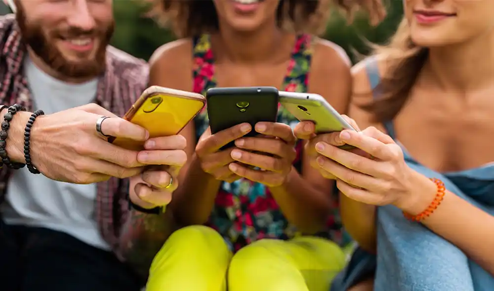 három ember ülve, okostelefonnal a kezükben Landventure városi nyomozós játékot játszanak