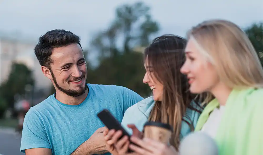 két nő és egy férfi városnéző sétán városfelfedező kalandjátékot játszik Győrben egy okostelefonnal