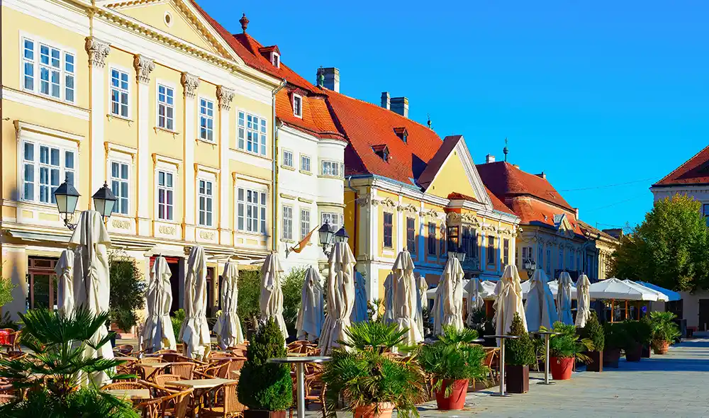 a győri Széchenyi tér napfényben fürdő, teraszos vendéglőivel