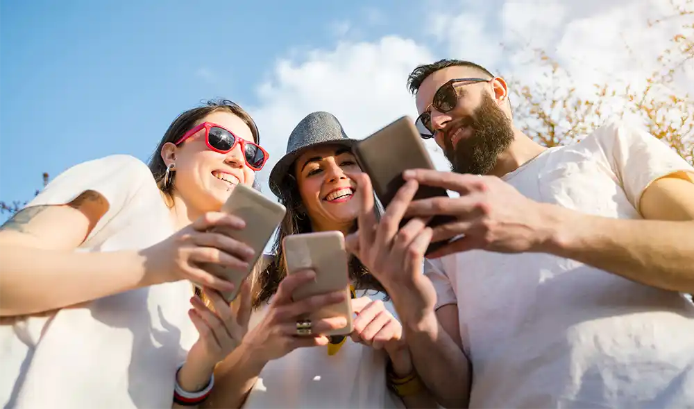 három fiatal Kecskemét belvárosában Landventure szabadtéri nyomozós játékot játszik okostelefonon