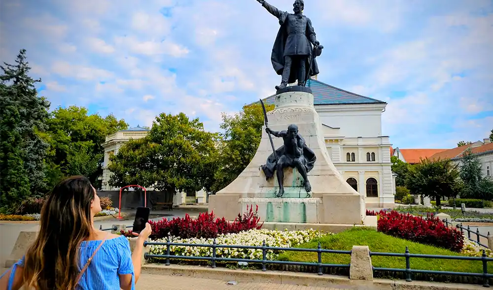 egy nő a kecskeméti Kossuth-szobornál egy izgalmakkal teli Landventure nyomozós játékot játszik