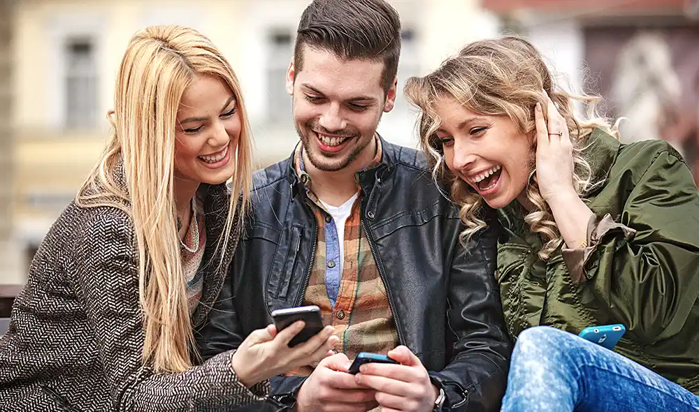 two women and a man are playing the Landventure scavenger hunt on their smartphones in Munich's city center