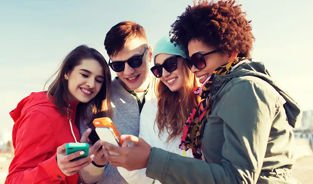 four young people are playing the Landventure scavenger hunt on their smartphones in Munich's city center