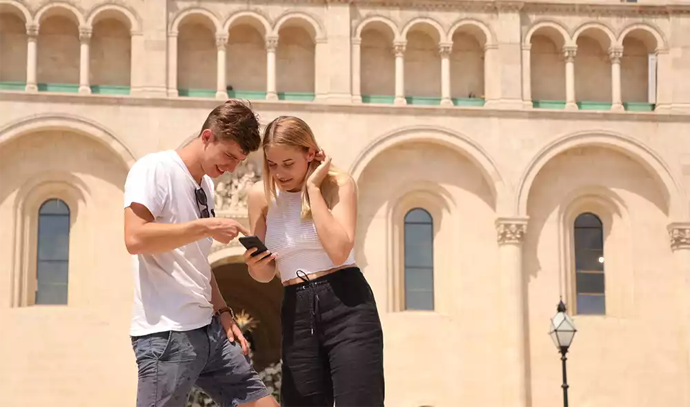 a young couple playing the Landventure detective game on a smartphone in downtown Pécs