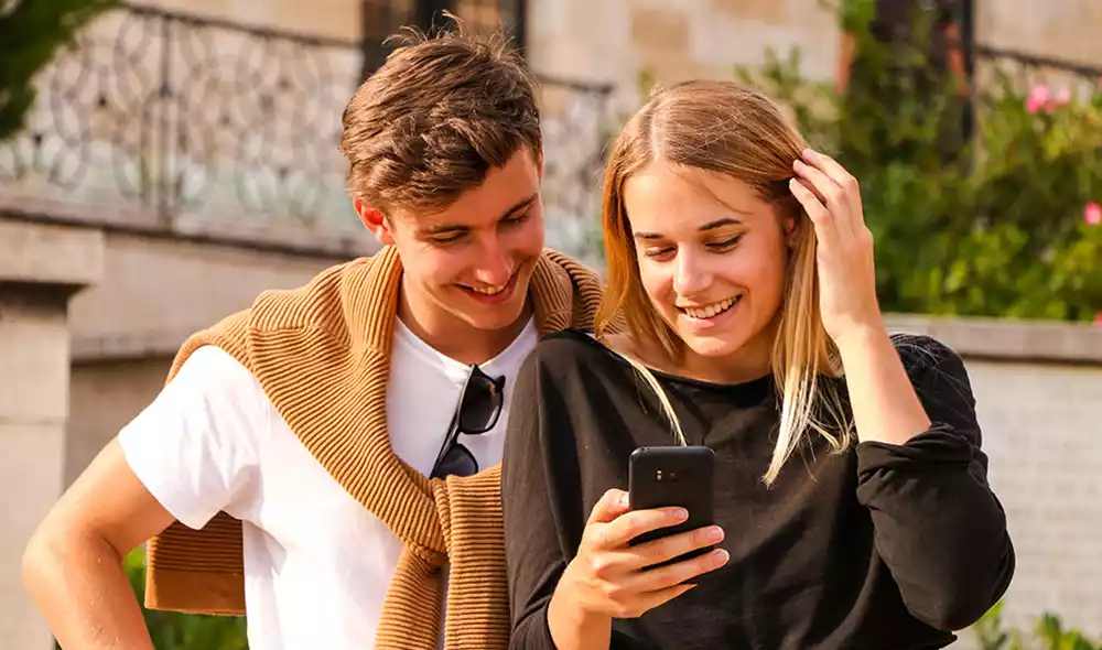 a happy young couple in downtown Pécs playing the Landventure detective game on a smartphone