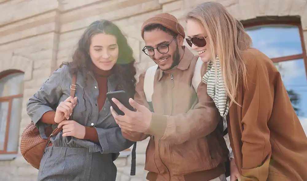two women and a man are playing a Landventure scavenger hunt on their smartphones in Salzburg’s city center