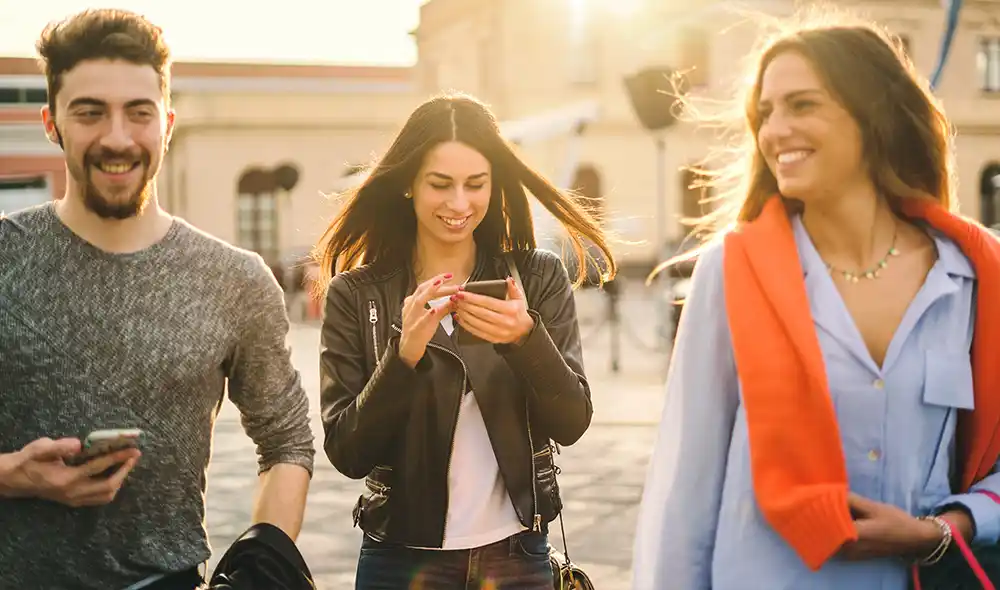 two women and a man are strolling through Salzburg while playing a Landventure scavenger hunt on their smartphones