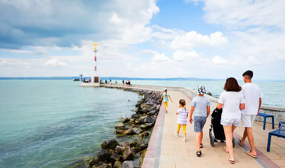 egy család a siófoki mólón sétál a Béke Jóságos Angyala szobor felé, ami egy izgalmas Landventure küldetés helyszíne is