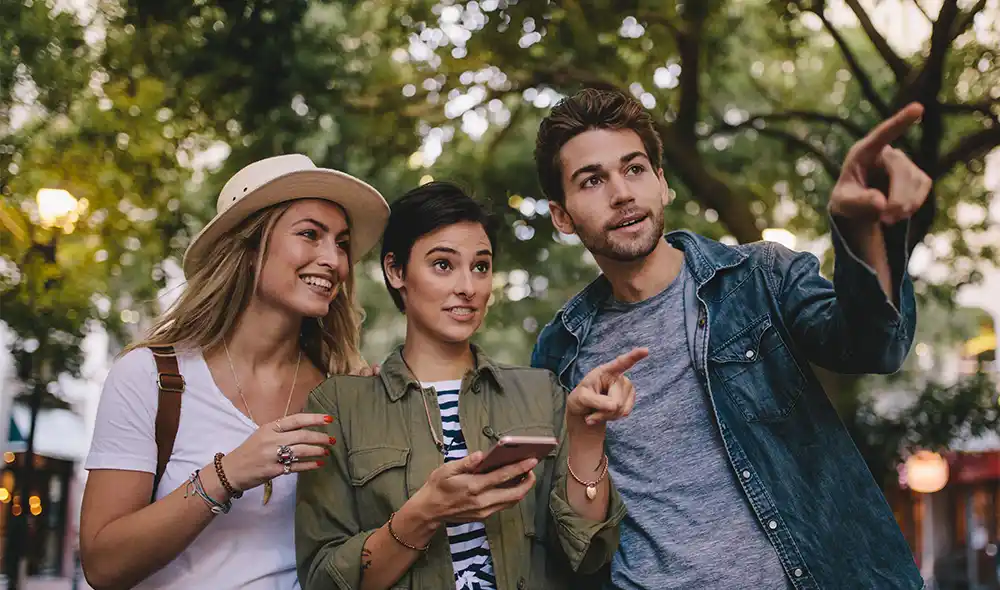 drei junge Leute spielen auf ihrem Smartphone die Landventure Stadtrallye im Stadtzentrum von Wien