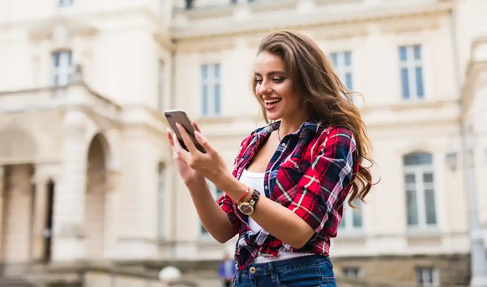 ein junges Mädchen in einem karierten Hemd spielt die Landventure Stadtrallye auf ihrem Smartphone in Wien