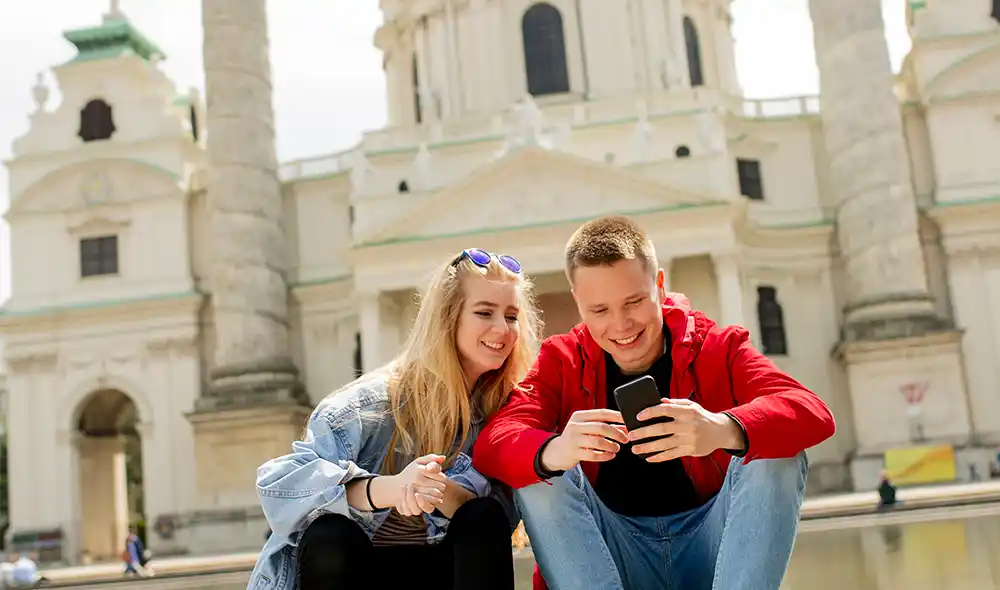 ein junges Paar spielt Landventure Schnitzeljagd und Stadtrallye vor der Karlskirche in Wien