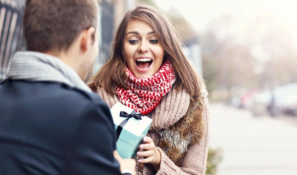 Erlebnisgeschenke für Frauen: Eine Frau öffnet voller Freude ihr Geschenk, in dem sich ein Landventure-Geschenkgutschein befindet