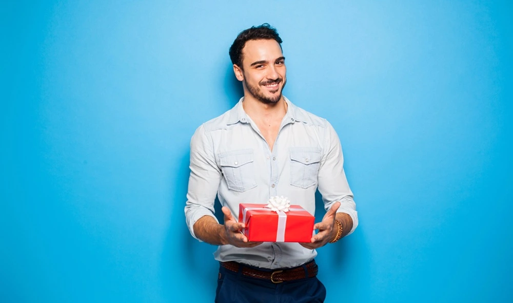 Erlebnisgeschenke für Männer: Ein Mann hält ein Geschenk, in dem sich ein Landventure-Geschenkgutschein verbirgt