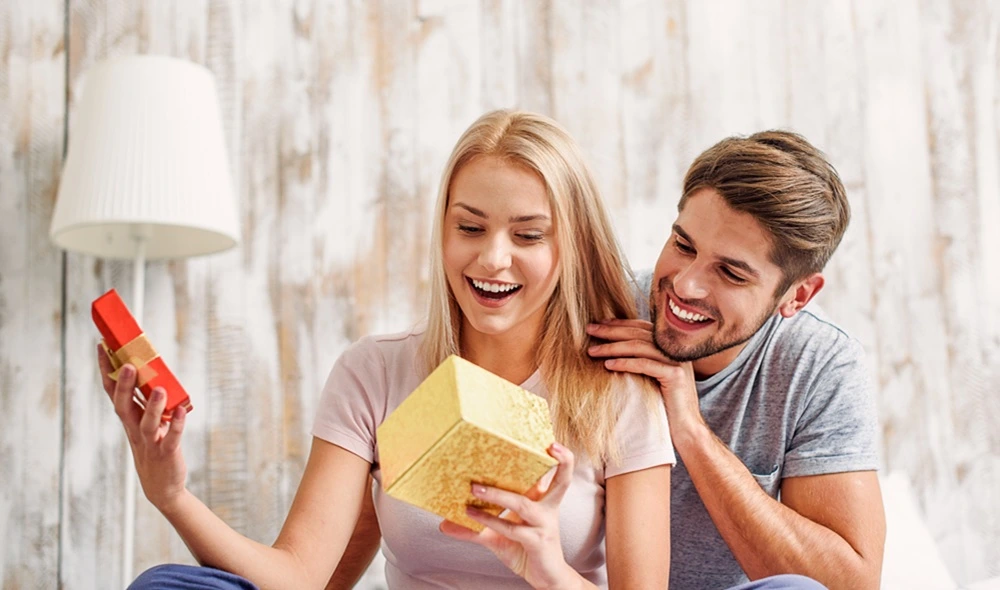 best experience gift vouchers: a young couple exchanging presents, including a box with a Landventure voucher