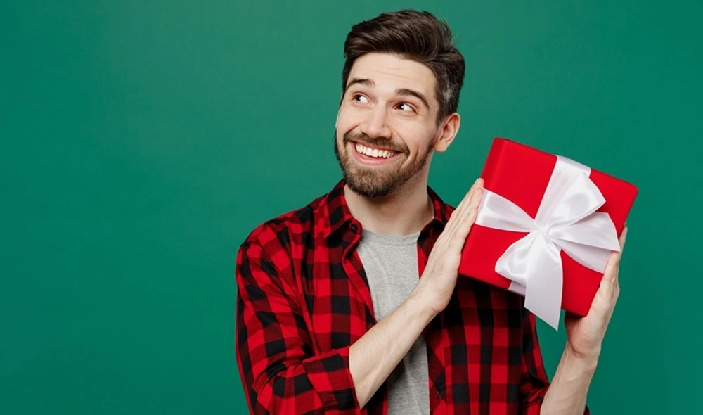 experience gift ideas for men: a man holding a red gift box that hides a Landventure gift voucher